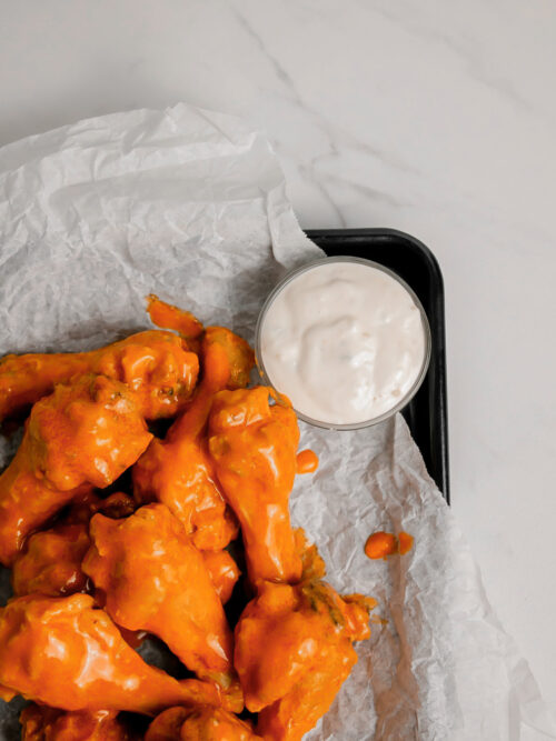 Homemade garlic buffalo wings on a tray with ranch