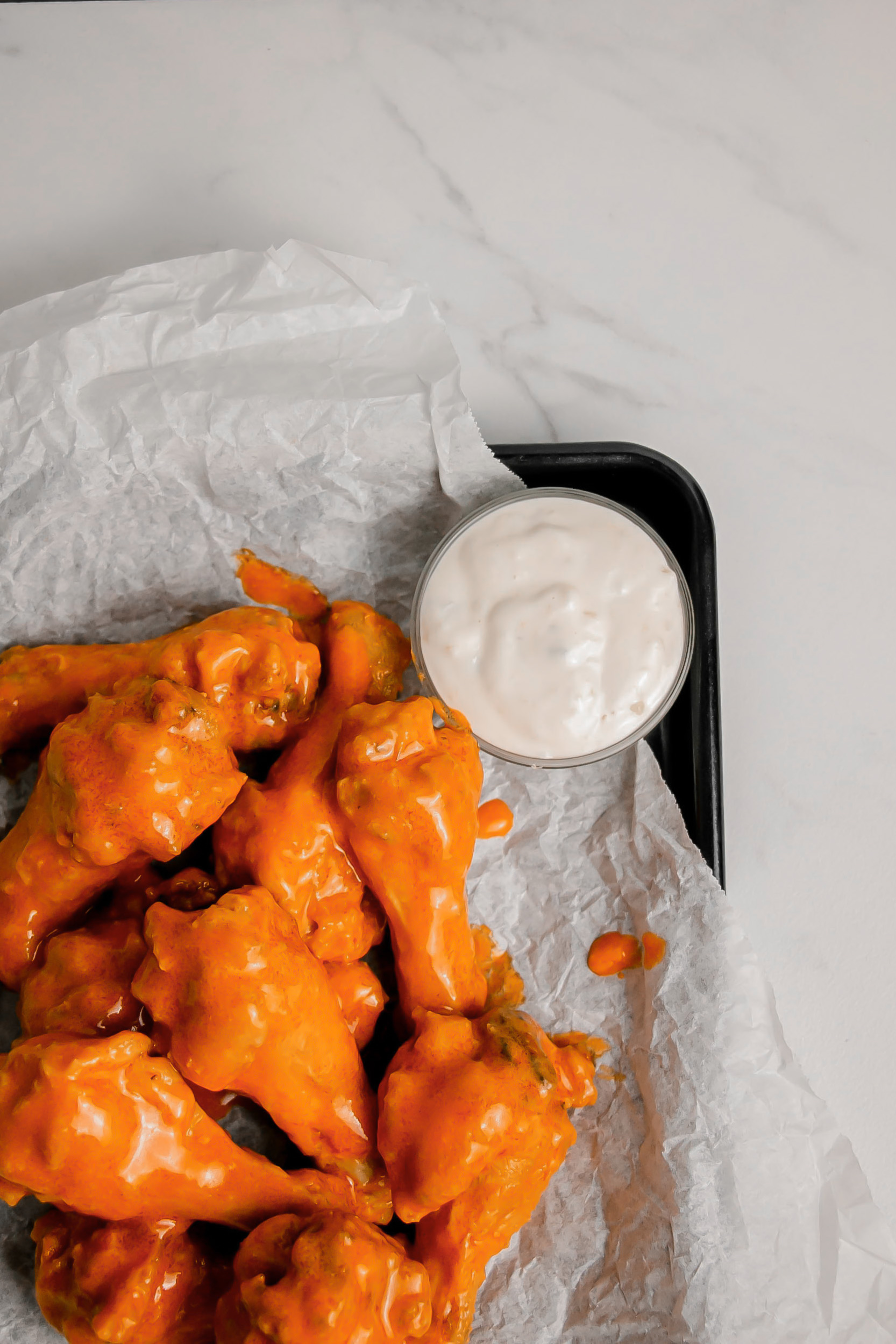 Homemade garlic buffalo wings on a tray with ranch