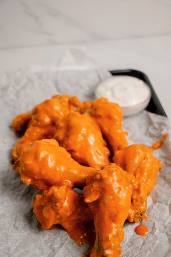 Homemade garlic buffalo wings on a tray with ranch side view