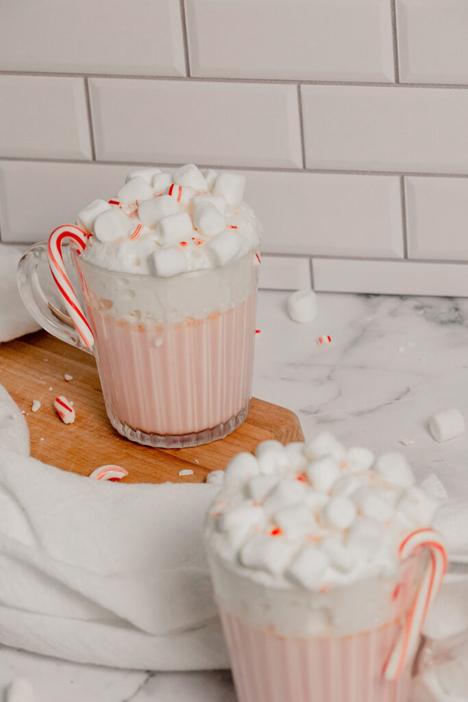 Homemade pink peppermint hot cocoa with crushed candy canes, whipped cream, and marshmallows