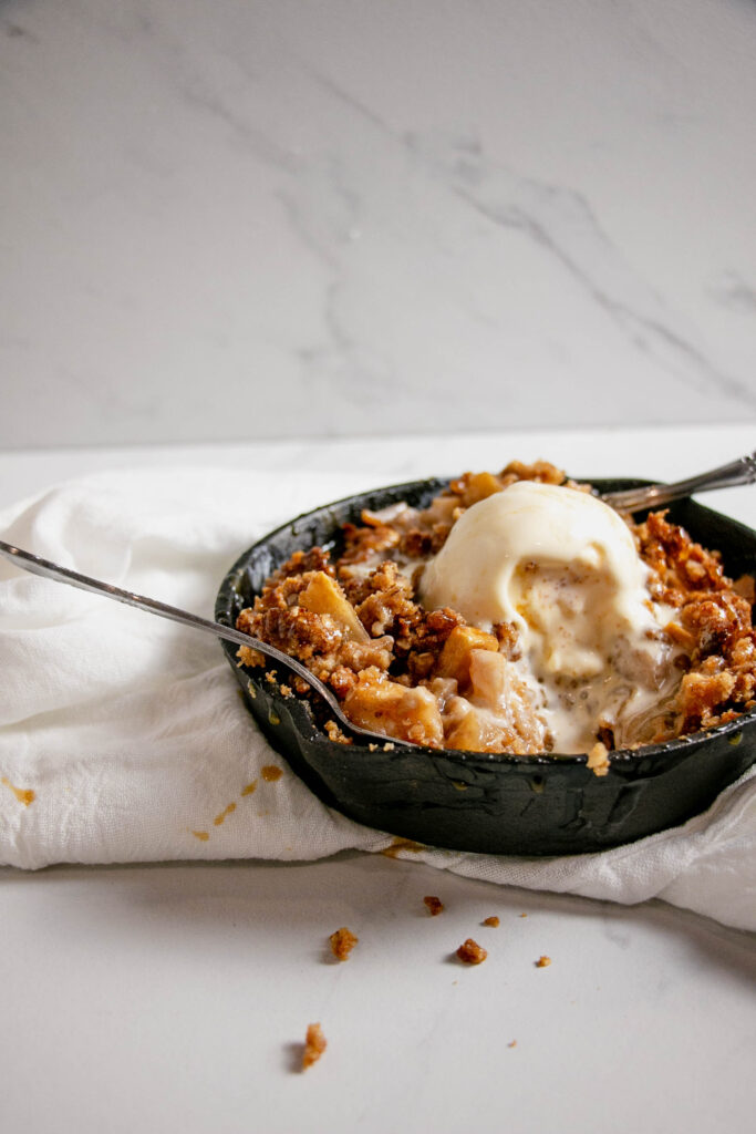 Homemade caramel apple crumble topped with ice cream side view