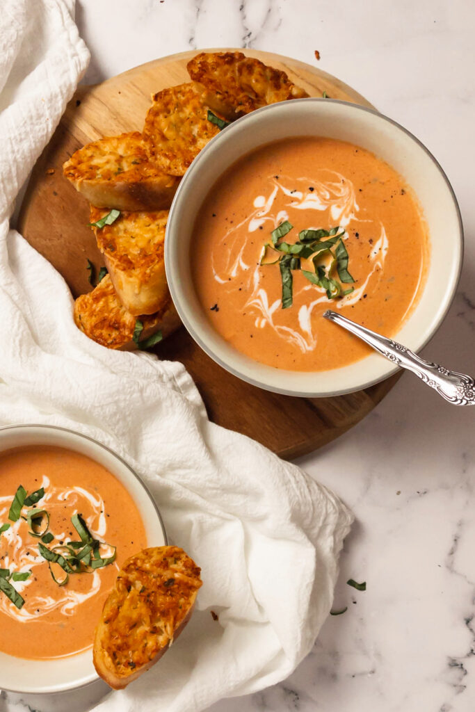 Homemade creamy tomato basil soup in bowls top view