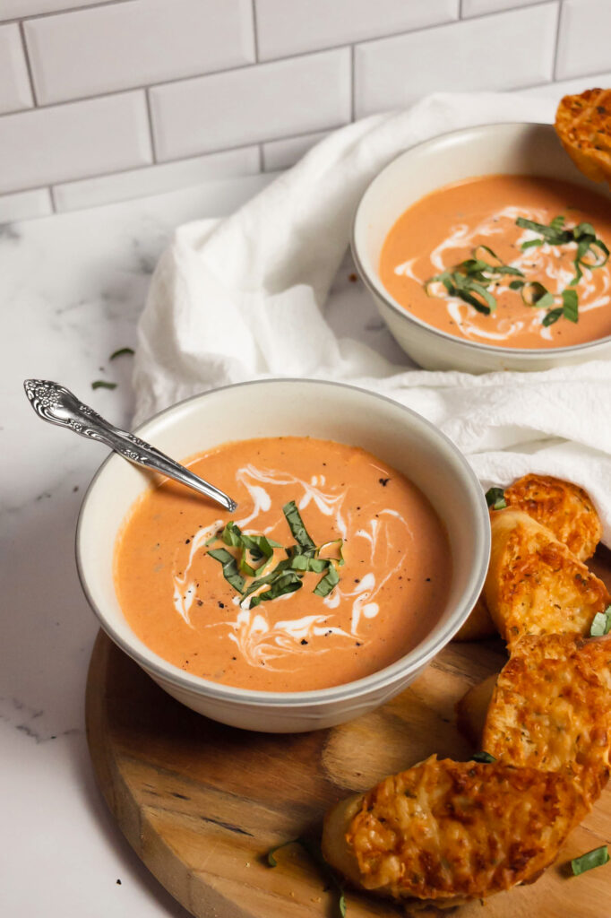 Homemade creamy tomato basil soup in bowls side view