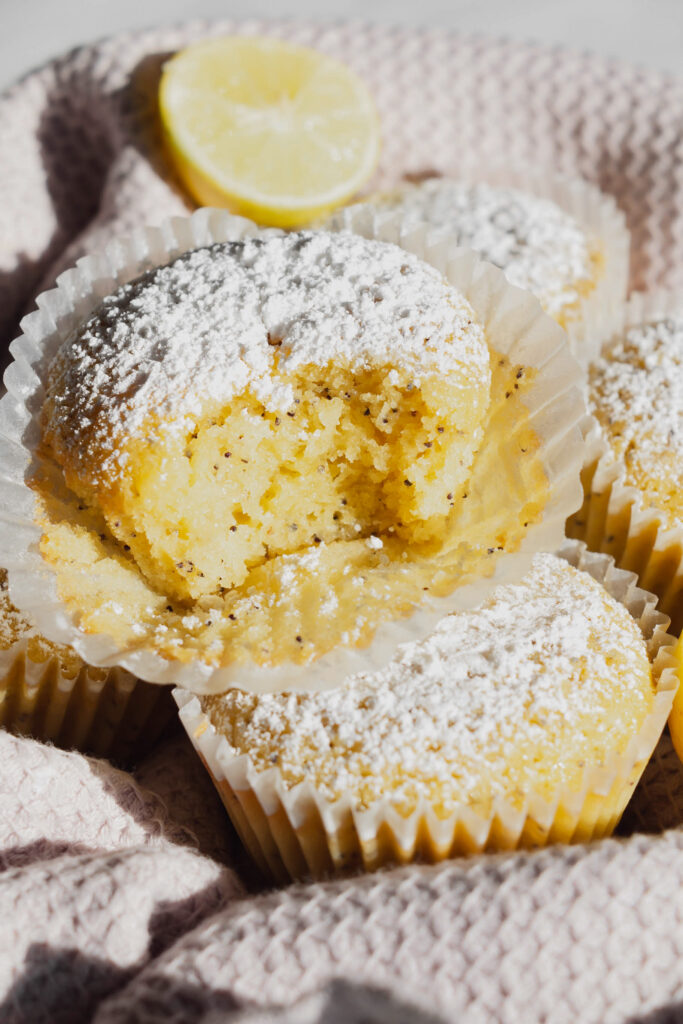 homemade lemon poppy seed muffins with a bite in a basket